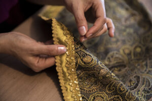 Close-up of Aari embroidery work with needle and thread on silk fabric